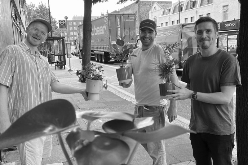 Three of the undefined team on a London street, each holding a pot plant